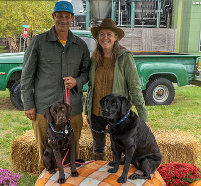 Moxie and Maple posing with Sam and Mariah Calagione on a hay bale at Punkin Ale Fest 2023