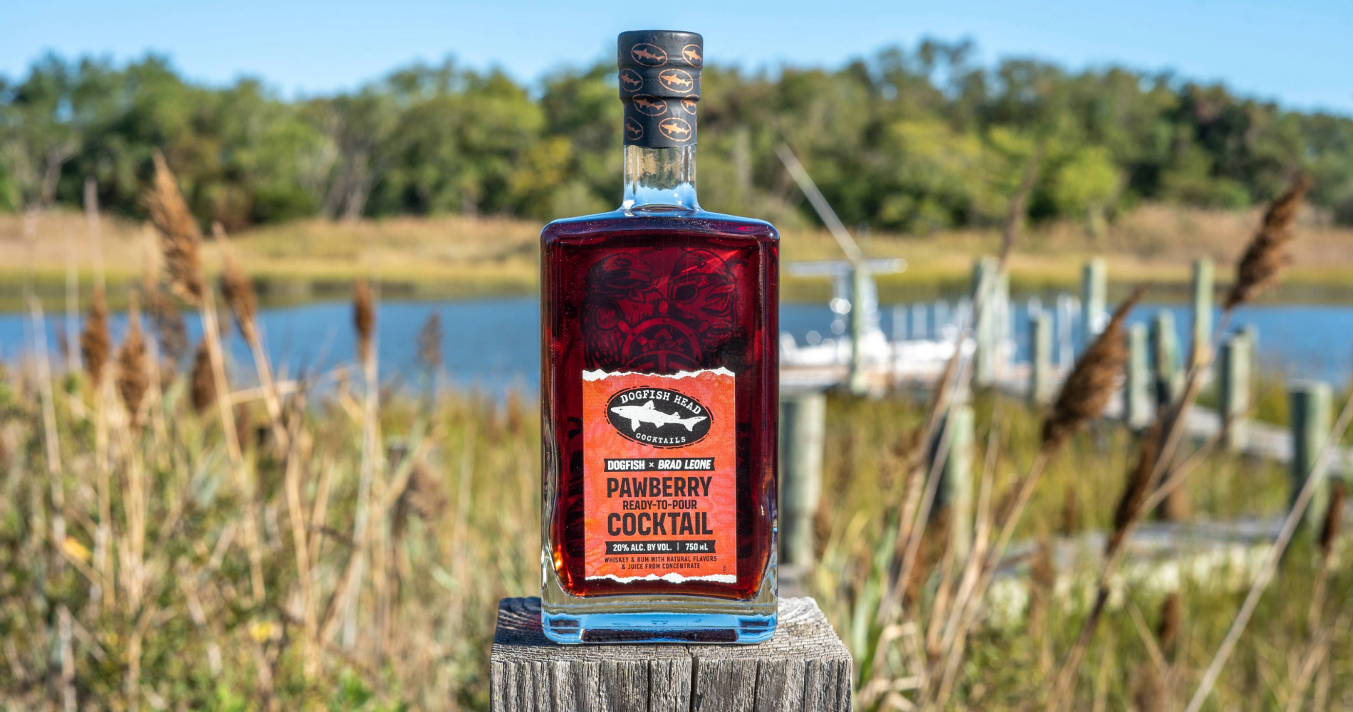 Bottle of Pawberry Ready-To-Pour cocktail on a deck with a boat behind it