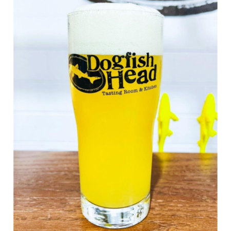 Dogfish Head beer Poised For Flight that is hazy, pale gold with a white head in a pint glass