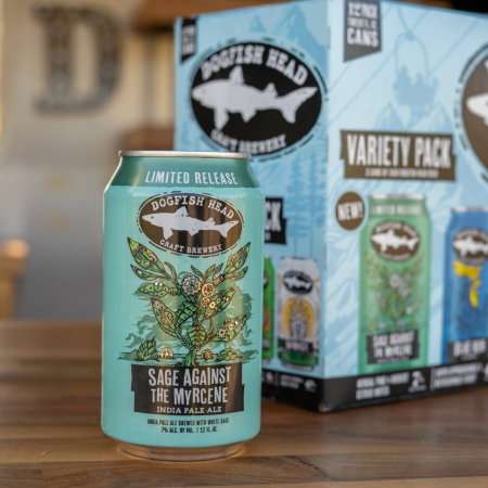 12 oz can of Dogfish Head Sage Against The Myrcene in a green can with cartoon sage artwork on a wooden desktop with a variety pack of beers behind it