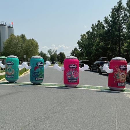 Four Dogfish Head inflatable beer can suits standing on a street 