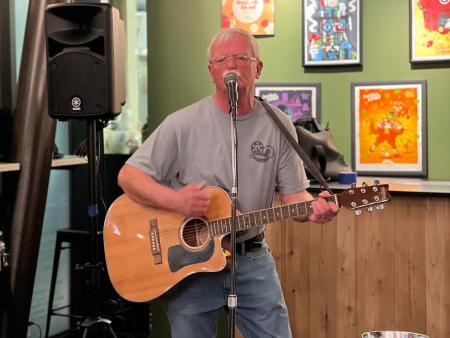 photo of a man playing an acoustic guitar and singing into a microphone