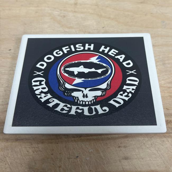 square ceramic coaster overhead image featuring Dogfish x Grateful Dead collaboration artwork with skull, shark and shield,